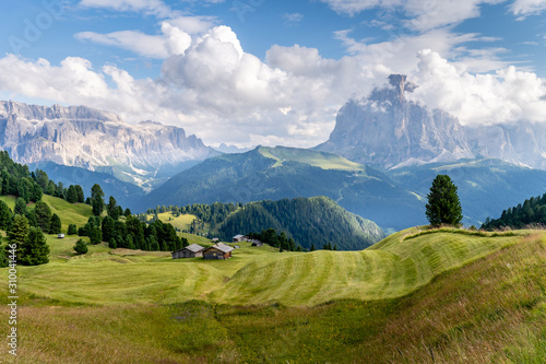 Hiking through the beautiful green meadows and a hut at the amazing Val Gardena valley in Dolomites mountains, Alps, Italy.
