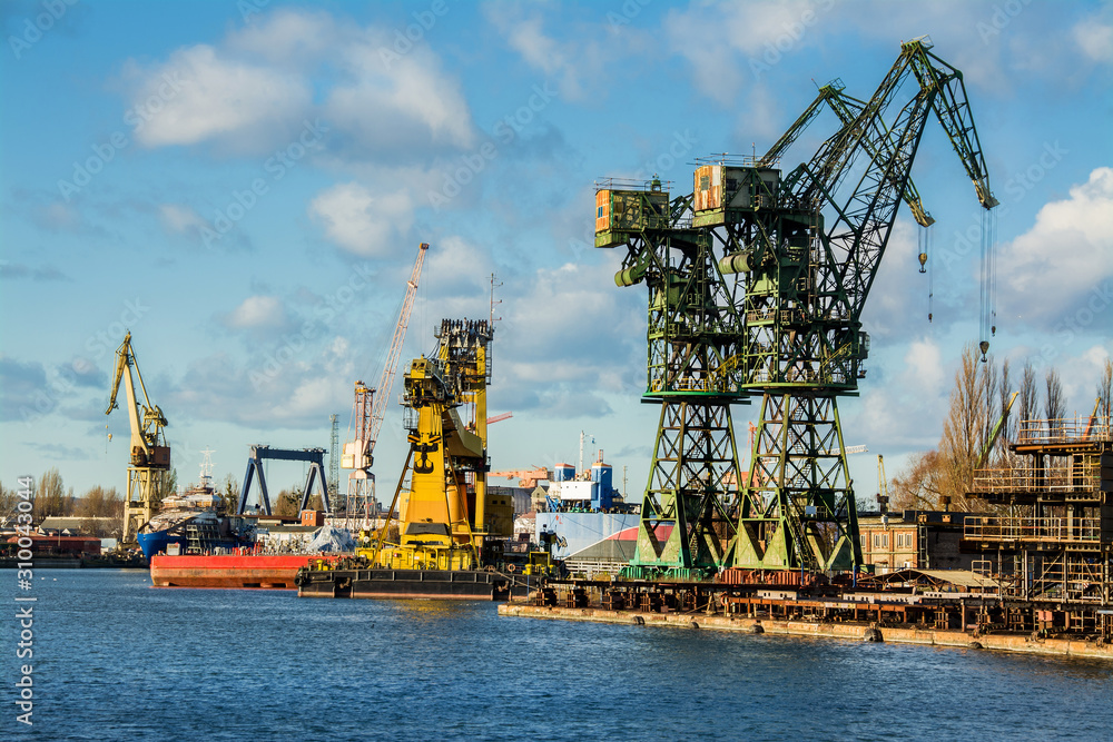 View of the shipyard with historical cranes in the industrial part of the city Gdansk (Gdańsk) in Poland (Polska). The shipyard is close to the old town. Peaceful Motlawa river.