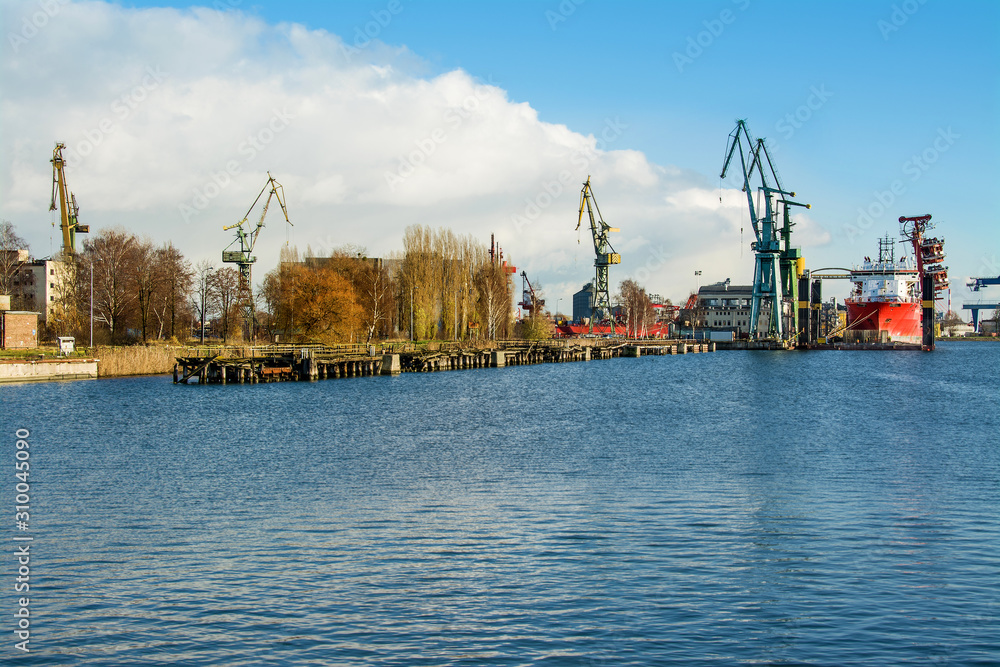 View of the shipyard with historical cranes in the industrial part of the city Gdansk (Gdańsk) in Poland (Polska). The shipyard is close to the old town. Peaceful Motlawa river.