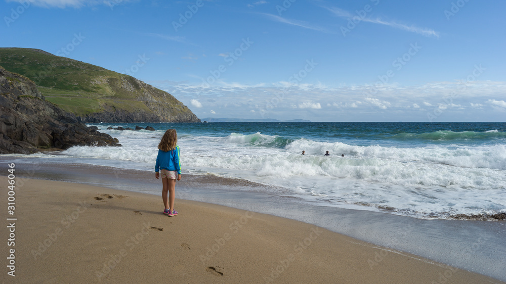 Girl watching family enjoying the waves of the ocean, Ballyferriter, County Kerry, Ireland