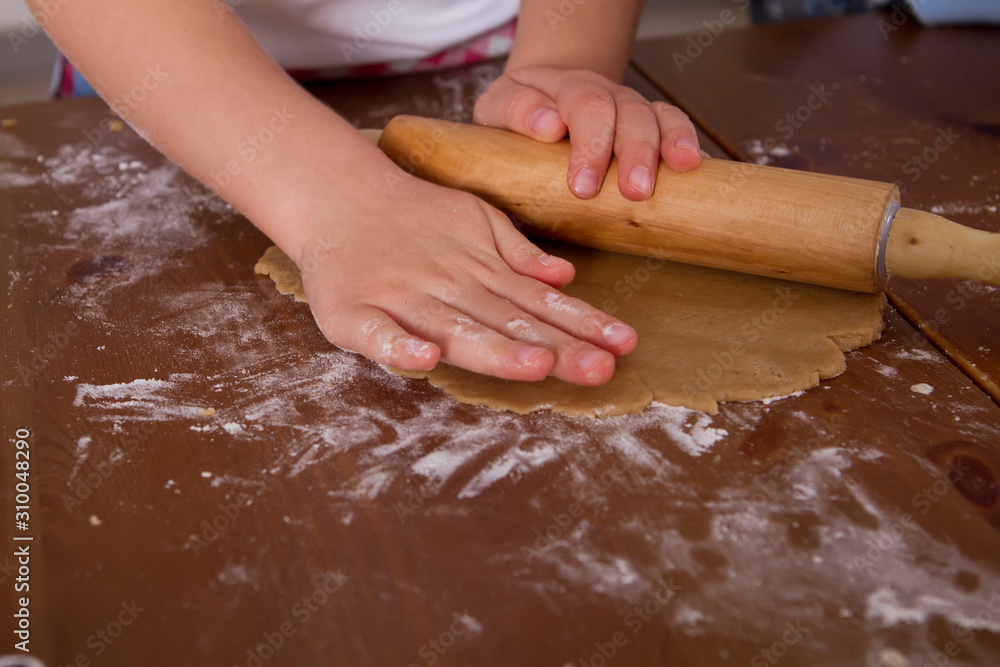 Cookie dough. preparation for gingerbread. A baby s hand rolls out a piece of dough with a rolling pin.