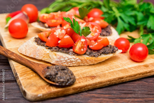 Fresh tasty bruschetta with truffle sauce, chili, parsley, tomates. Close view