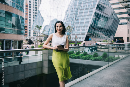 Smiling modern Asian businesswoman with organiser in office building