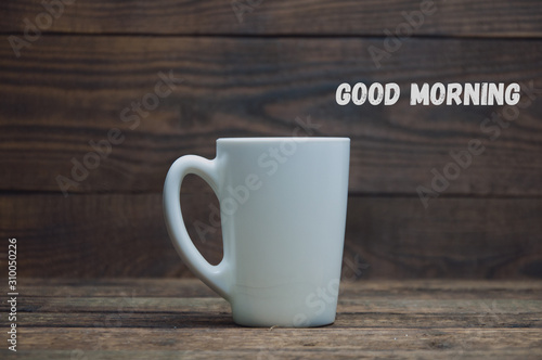 A white cup stands on a wooden table. Tea and coffee in the morning