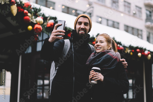 Smiling young couple taking selfie on smartphone at Christmas