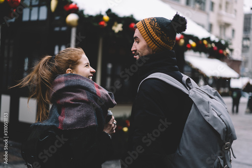 Young smiling couple with backpacks walking at Christmas