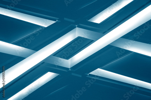 Lamps on dropped ceilings. Abstract modern architecture of an office building interior resembling glowing girders. Technological or geometric background with parallel lines.