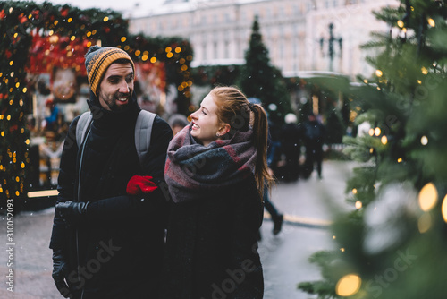 Young couple holding hands and walking on decorated street