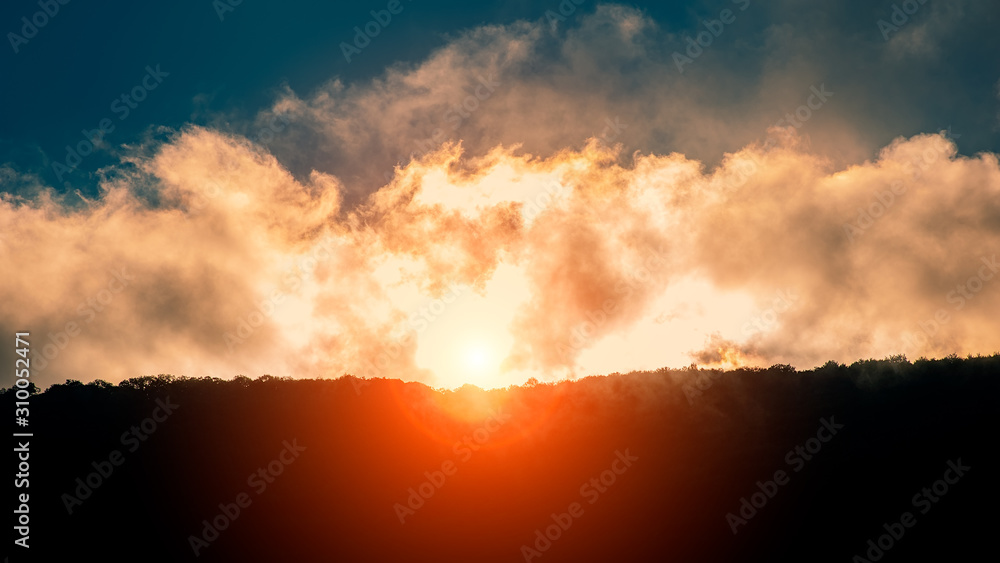 tops of the mountain lit by sunlight at sunset in the clouds, panoramic landscape.