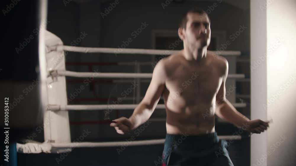 Box training - a man standing on the ring and warming up - jumping over the jumping rope Box training - a man standing on the ring and warming up - jumping over the jumping rope