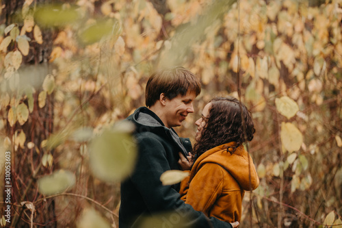 Young man and woman kiss in the autumn forest.