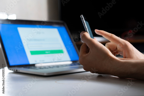 Fotografie holding a phone and working using laptop, log in on website, double-factor authe