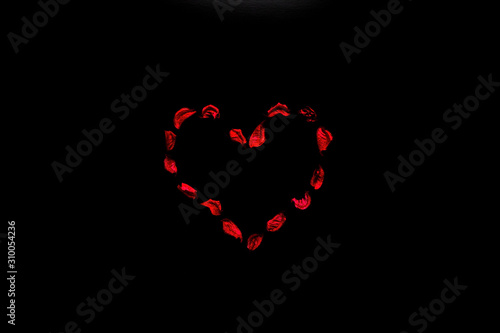 Red heart of flower petals on black background. Symbol of passion and love.