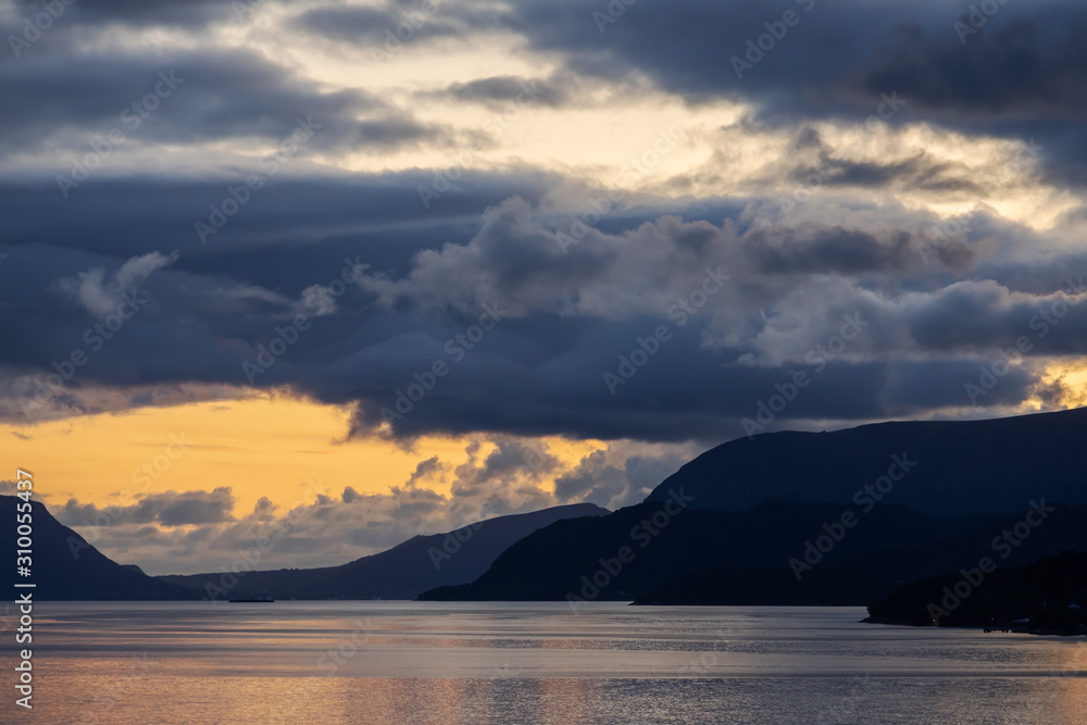 Sonnenuntergang mit dunklen Wolken im Storfjord in Sunnmøre, Norwegen