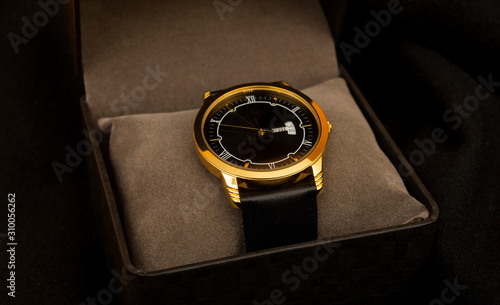 Luxury style golden hand watch in gift box on black background