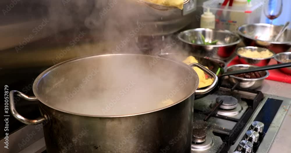 Chef takes out dumplings from a pot with boiling water and bounces them with a special stew in the pan. Chef takes out dumplings from a pot with boiling water and bounces them with a special stew in the pan.