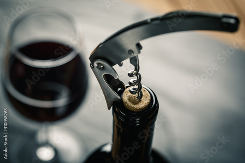 Stainless  wine corkscrew in a cork of wine bottle neck on a black slate background photo