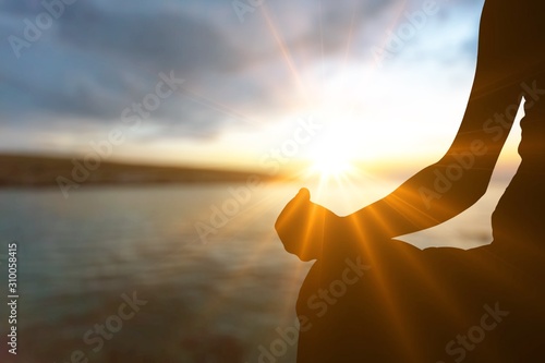 Human silhouette meditating at sunset, yoga relax concept