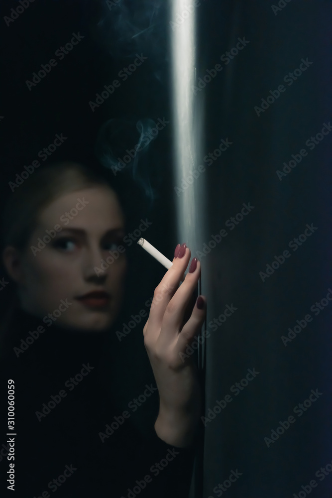 Obraz premium Retro 1940s woman with cigarette in black turtleneck sweater leaning against wall.