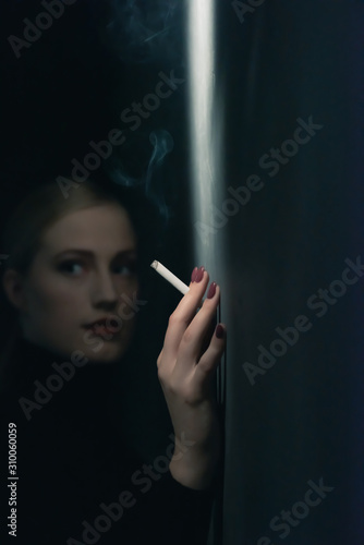 Retro 1940s woman with cigarette in black turtleneck sweater leaning against wall.