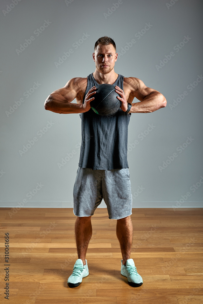 Strong man doing exercise with med ball. Photo of man perfect physique on grey background. Strength and motivation. Strong man doing exercise with med ball. Photo of man perfect physique on grey background. Strength and motivation.