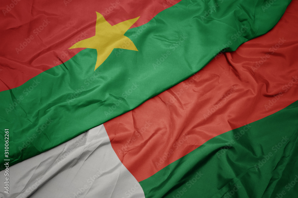 waving colorful flag of madagascar and national flag of burkina faso.