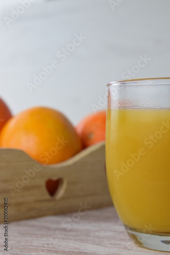 Vaso de zumo, fondo bandeja de madera con naranjas