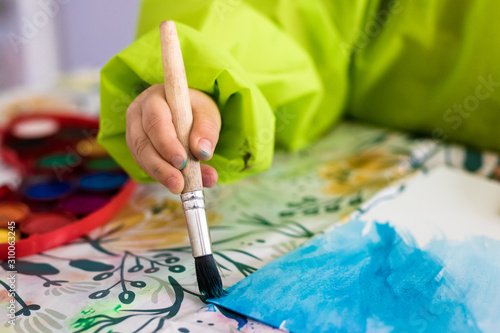 Child's hand painting blue picture with a brush