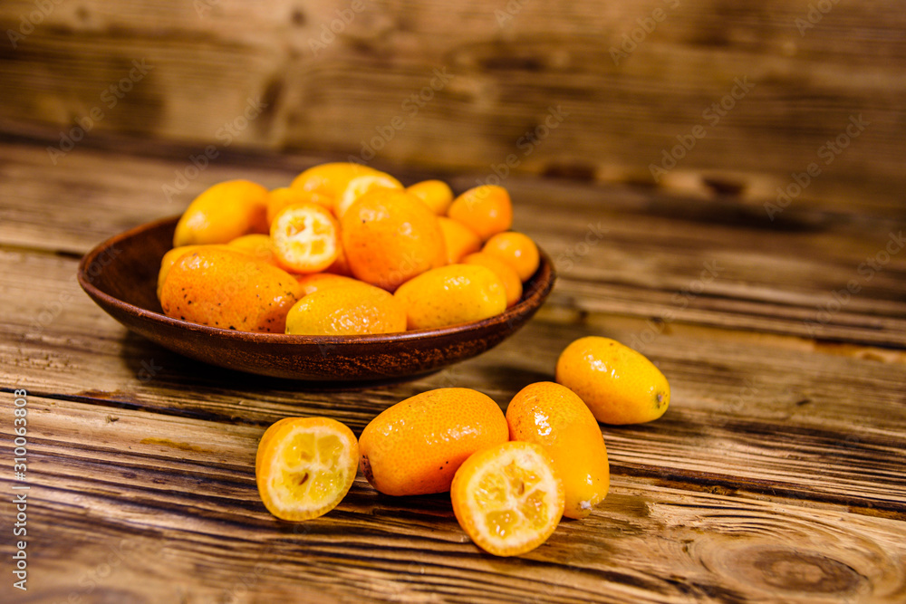 Plate with kumquat fruits on wooden table Plate with kumquat fruits on wooden table