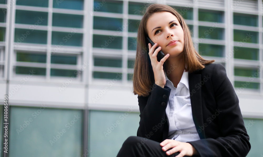 Portrait of a young woman talking on the phone sitting on a bench outdoor Portrait of a young woman talking on the phone sitting on a bench outdoor
