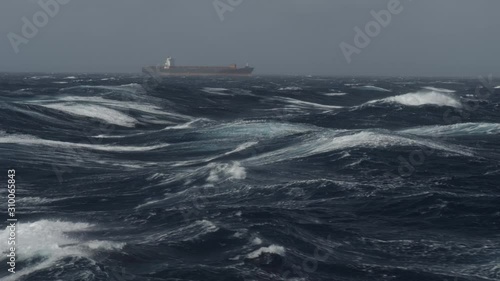 Large container ship heading in rough sea on tailwind