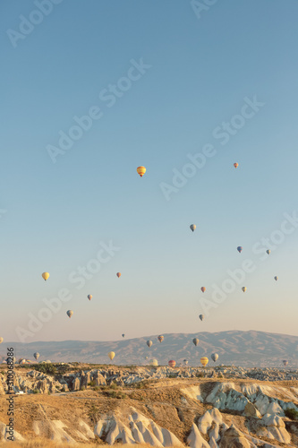 Aerial shot of hot air balloons soaring in the sky. Sunny morning in Cappadocia, Turkey. Famous air tourist attraction.