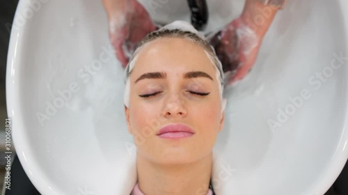 Close up of master hairdresser washing woman hair in beauty salon