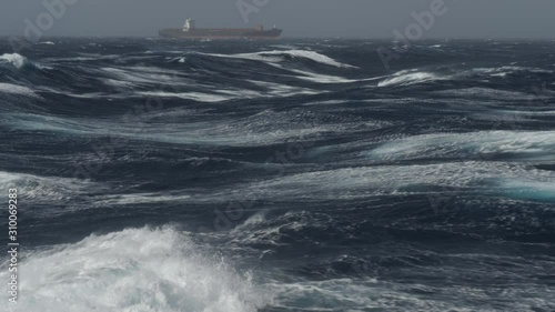 Large container ship heading in rough sea on tailwind