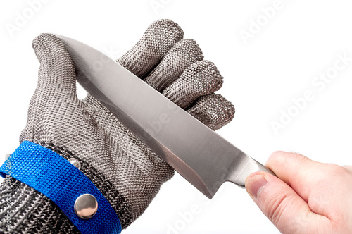 Obraz na płótnie Work safety and protective gear for safe working environment conceptual idea with hand wearing metal mesh protection glove and holding stainless steel knife by the blade isolated on white background w salonie