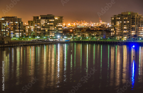 Melbourne, Australia - December 18, 2009: Port Melbourne beach area and Phillip bay at night shows Container terminal behind condominium complexes on shoreline of Sandrige quays.