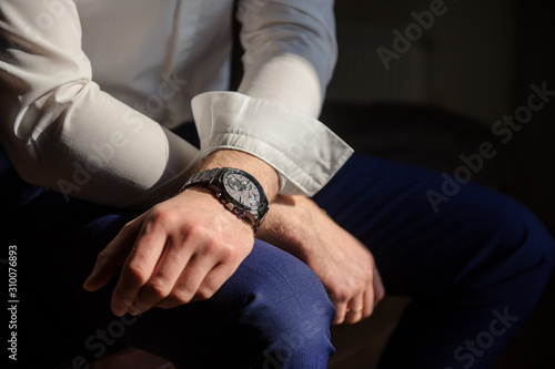 close up photo of groom's hands in a suit, a watch on the left hand