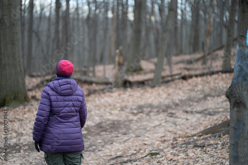 Woman hiking blue blaze trail in a hardwood forest in the winter.