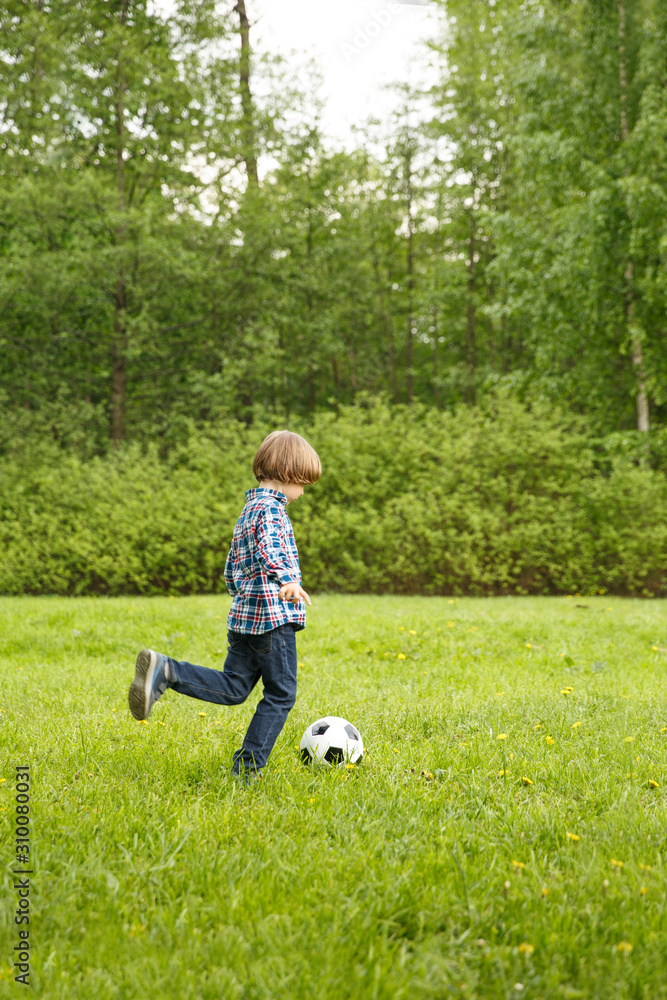 Sports Kid. Baby playing soccer ball in the park. Children play football. Family leisure.