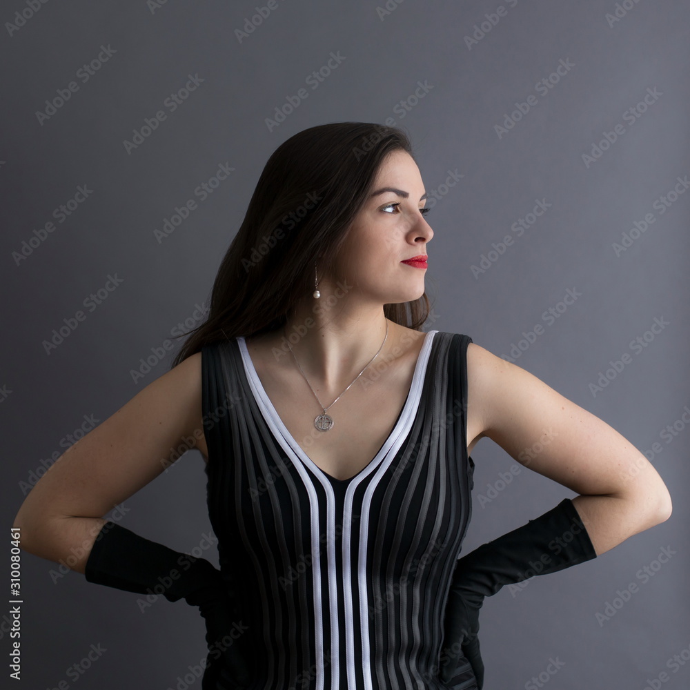 Medium square profile portrait of beautiful young brunette in graphic sleeveless black and white top and long evening gloves with hands on hips Medium square profile portrait of beautiful young brunette in graphic sleeveless black and white top and long evening gloves with hands on hips