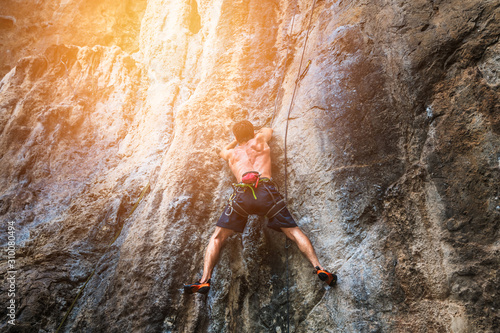 Adventure man traveler climbing on limestone cliff in Phra Nang cave beach, Krabi, Travel most famous place Thailand, Beautiful destination Asia, Summer holiday outdoor vacation trip