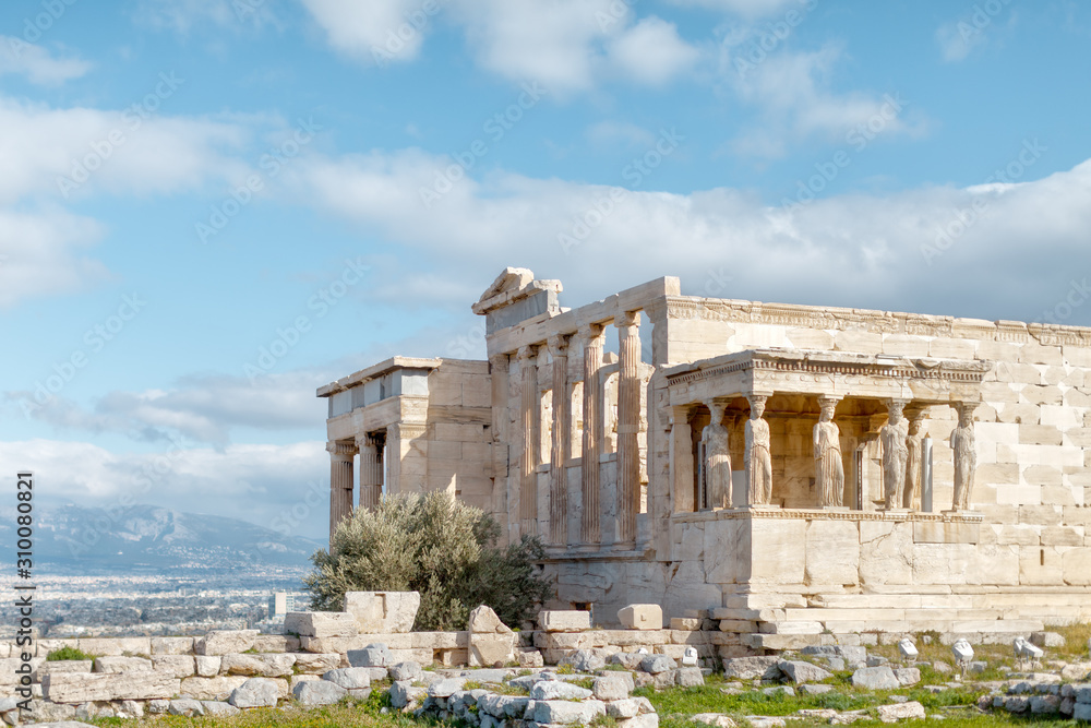 Panoramic view on the ruins of Erechtheion temple. Acropolis Hill in Athens. The surviving part of the colonnade. Figures of Caryatids Porch. Female statues. Blue sky. Traveling and vacation concept.