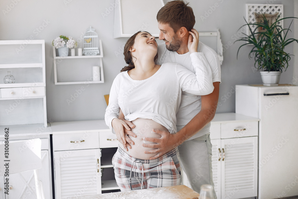 Cute couple in a kitchen. Lady in a white shirt. pregnant woman. Cute couple in a kitchen. Lady in a white shirt. pregnant woman.