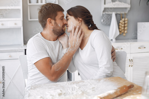 Cute couple in a kitchen. Lady in a white shirt. pregnant woman. © hetmanstock2