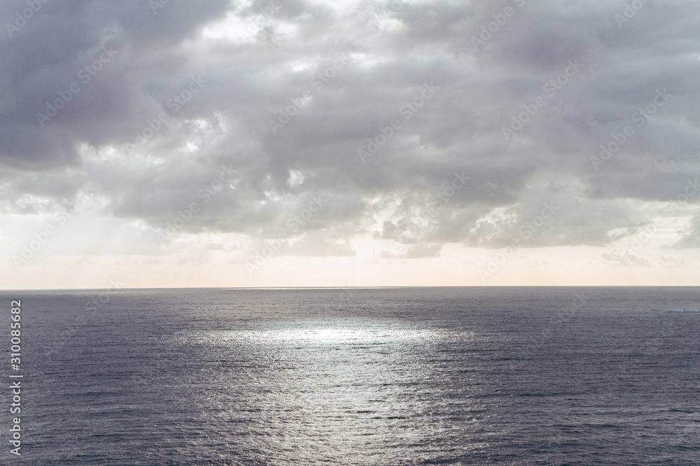 sea and cloudy sky sun rays circle on water surface