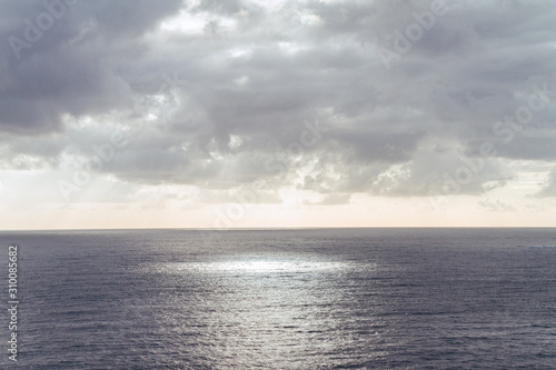 sea and cloudy sky sun rays circle on water surface