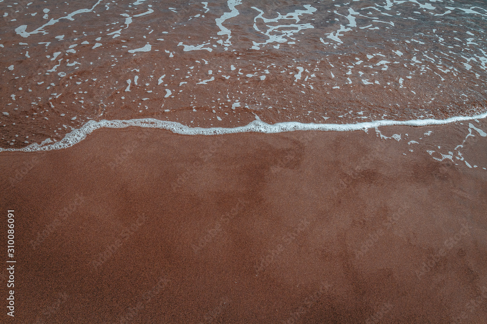 Fototapeta premium black sand beach at sundown with cloud reflections on wet sand waves clear water