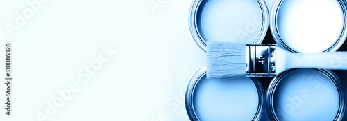 Brush with wooden handle on open cans on blue pastel background. Blue color. Renovation concept. Macro. photo