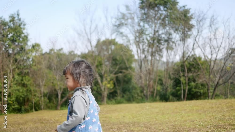 Happy Asian little child girl playing with her family in the garden on vacation. Happy Asian little child girl playing with her family in the garden on vacation.