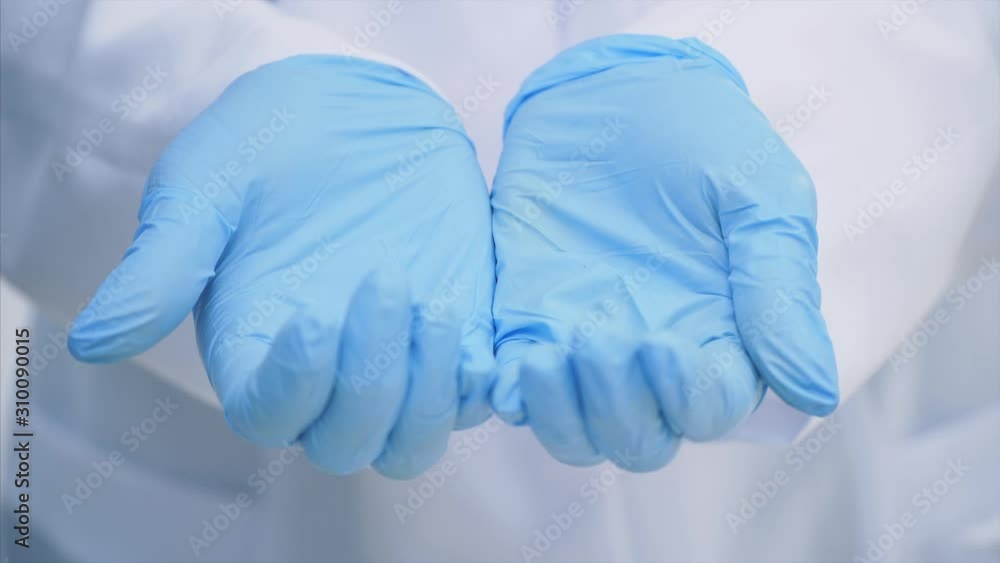 Many small white pill falling down into the doctor's hands dressed in the medical disposable gloves. Many small white pill falling down into the doctor's hands dressed in the medical disposable gloves.